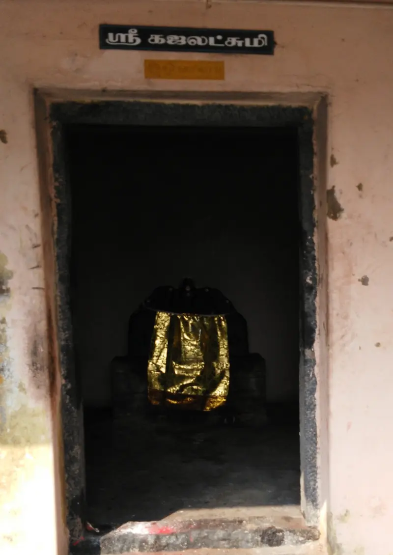 Small shrine with a name board and an idol covered in a gold cloth