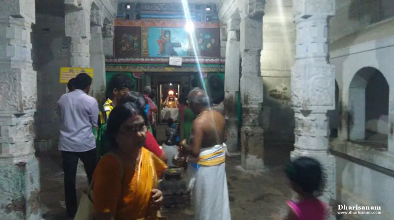 Worshippers stand among stone pillars; at the far end a lamp-lit shrine can be seen.