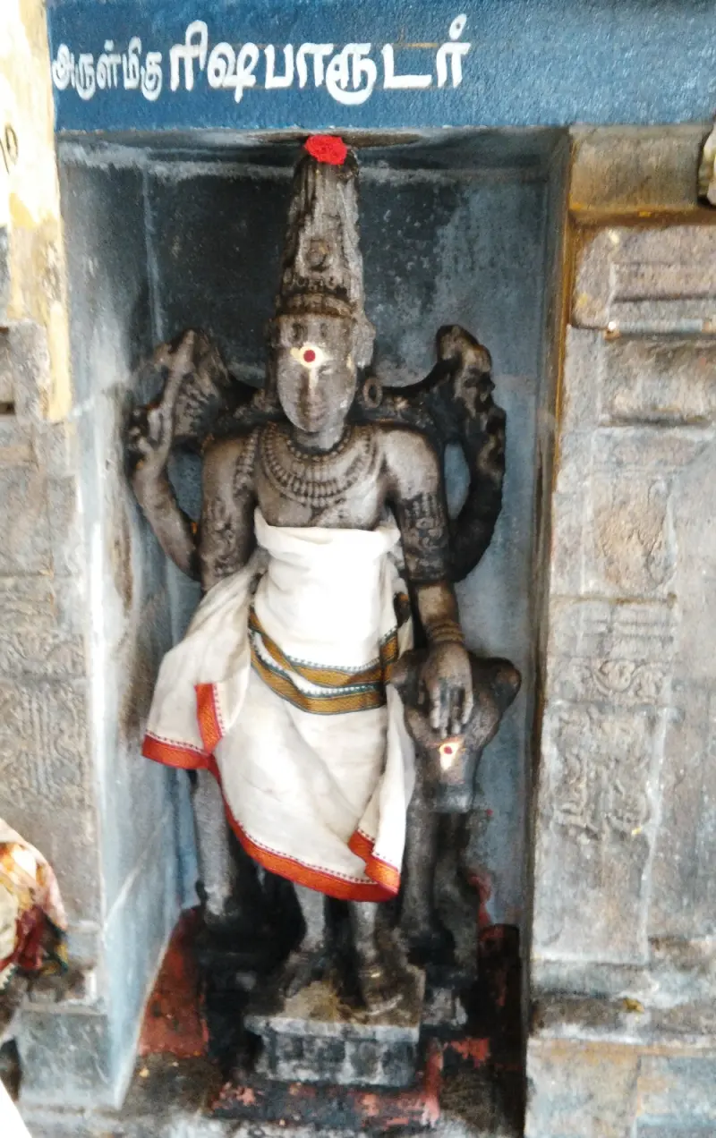 Stone Rishabaruder in white cloth with a bull beside him, in a niche beneath a blue Tamil name board