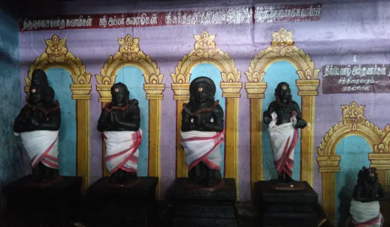 A row of black stone figures in white cloth standing in arched niches