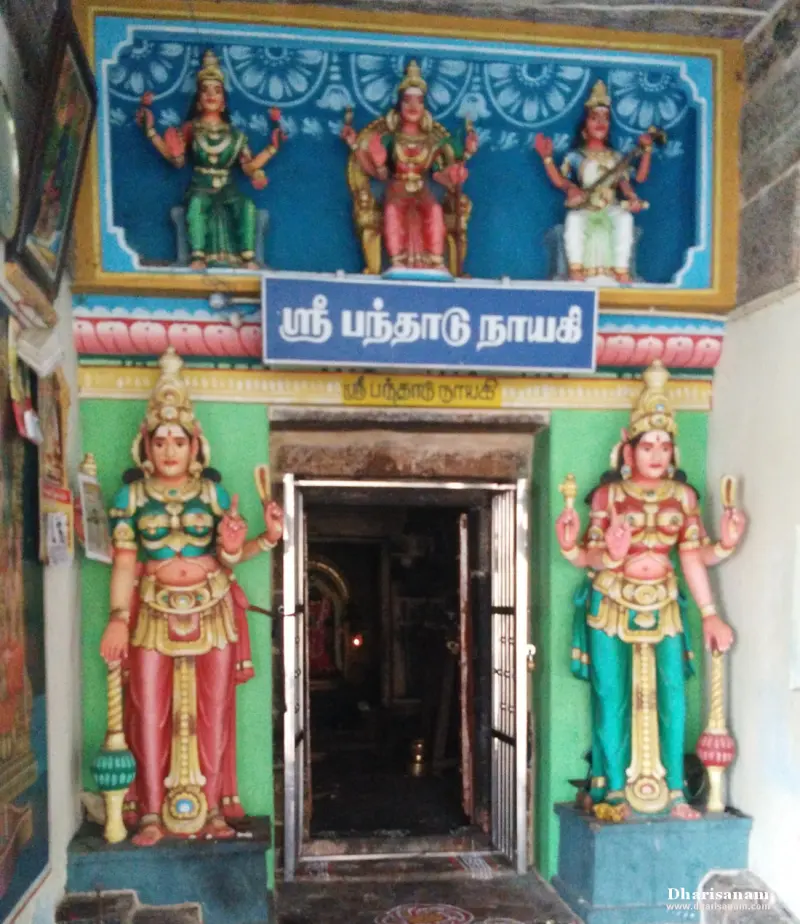 A shrine doorway under a blue name board, with two tall guardian figures beside it