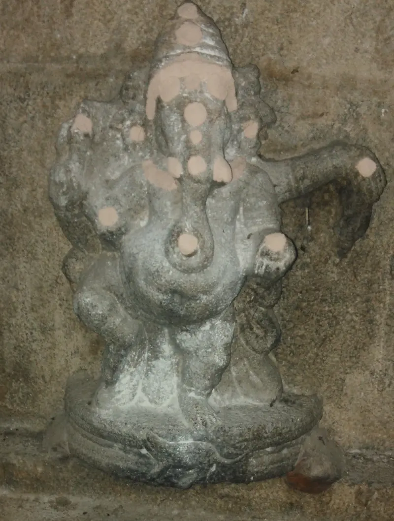 A small grey stone Vinayakar marked with spots of pink powder