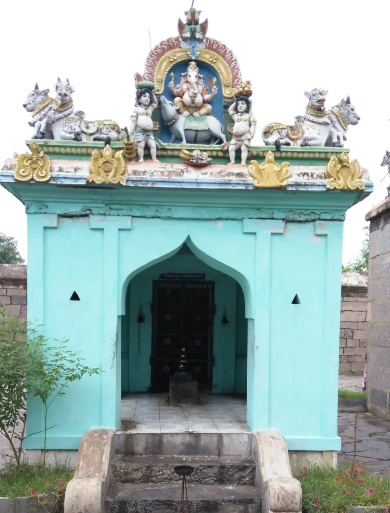 A small green shrine crowned with painted Vinayakar and bull figures