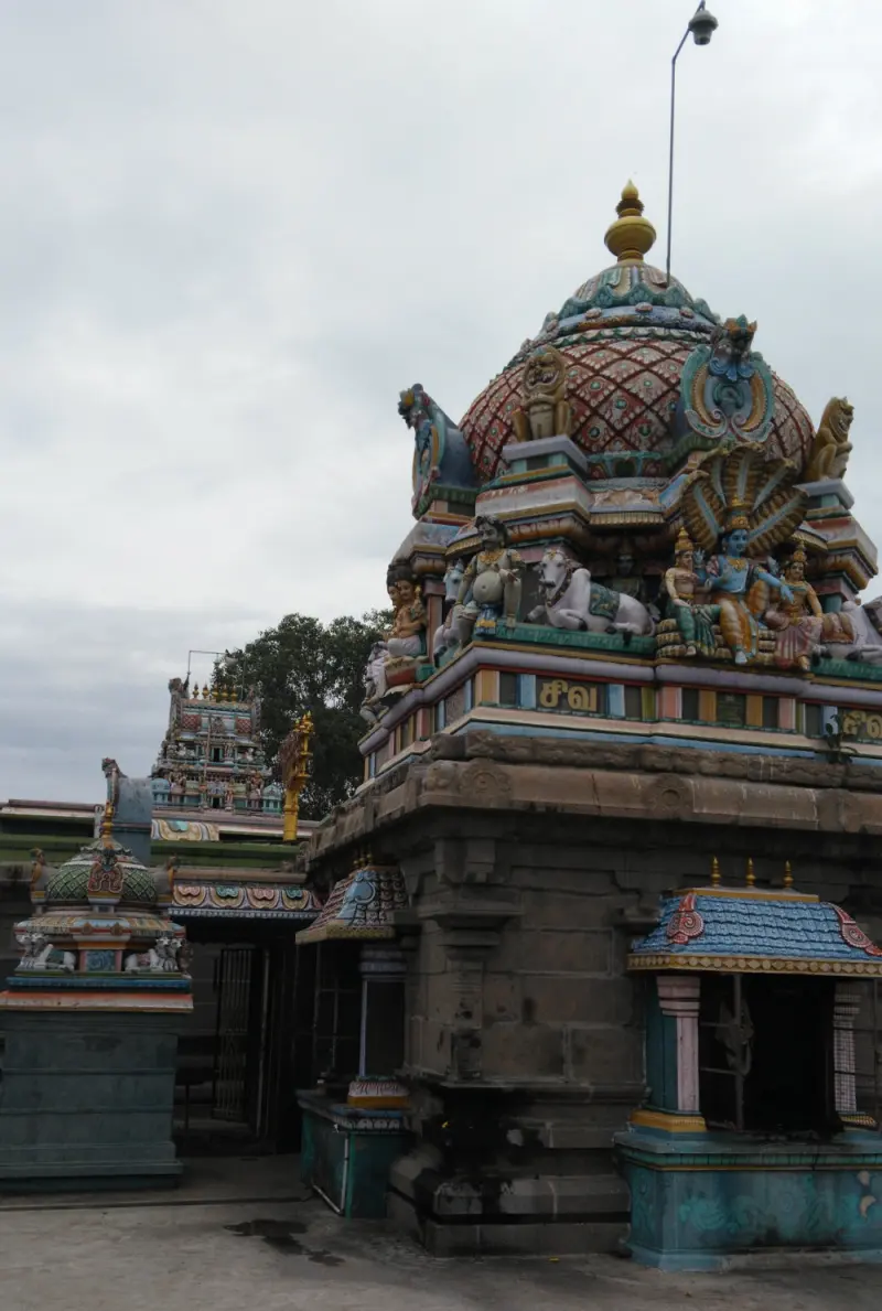 A stone shrine with a domed tower of painted figures, with a smaller shrine and another tower beside it.