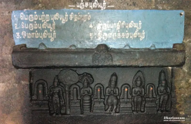 A carved stone panel of figures beneath a blue board headed Pancha Puliyur, listing five names