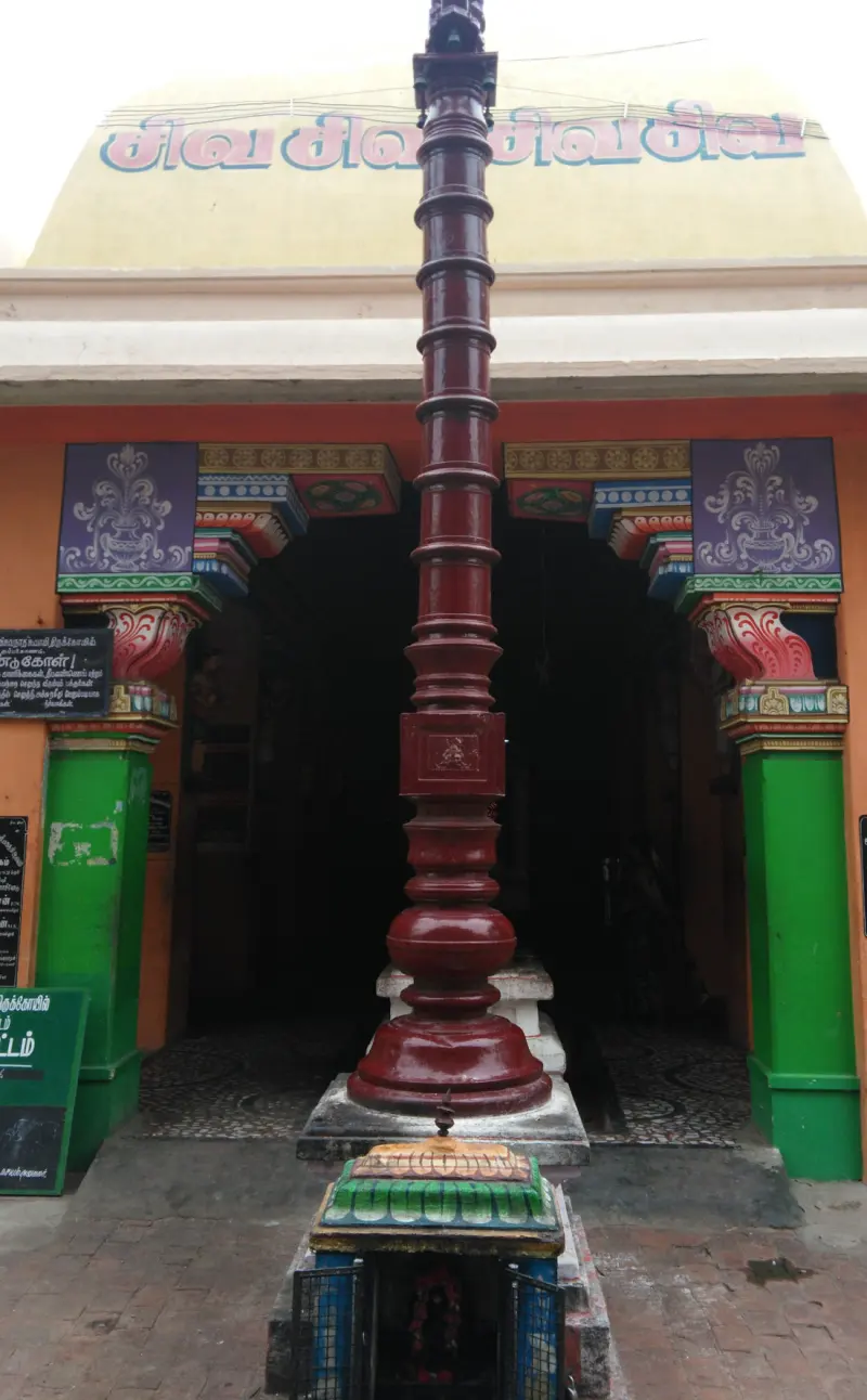 Tall red pole in front of a colourful doorway