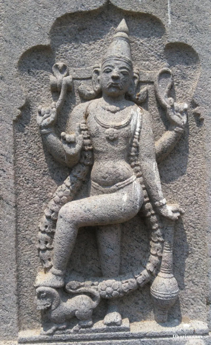 Granite relief of a standing four-armed figure with one raised leg, with serpents around it