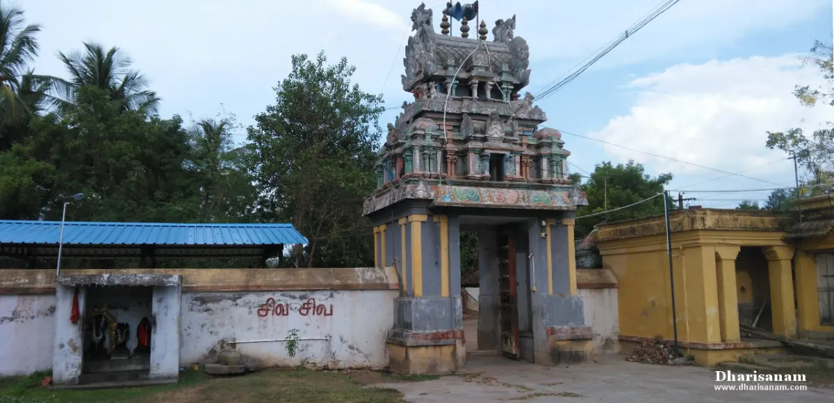 A small tiered tower over the temple gateway, with a shed and wall beside it.
