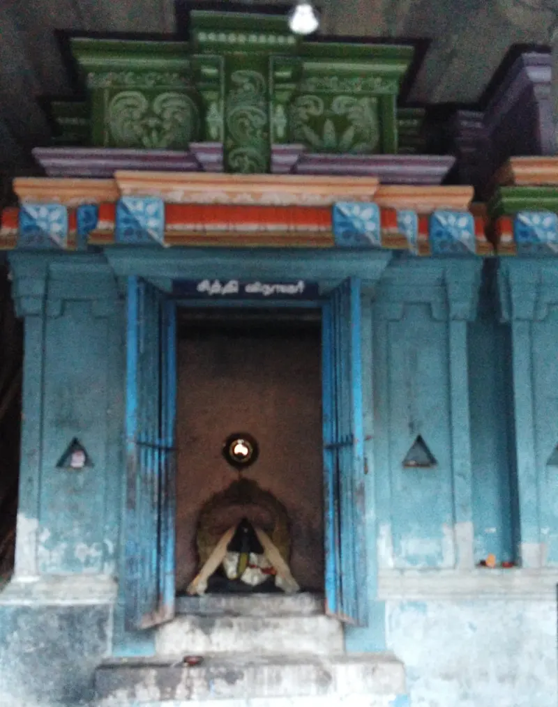Small blue-painted shrine with open doors and a name board in Tamil