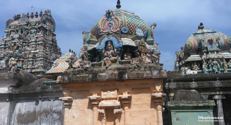 Colourful domed shrine roofs with sculpted figures, and a gopuram at the left