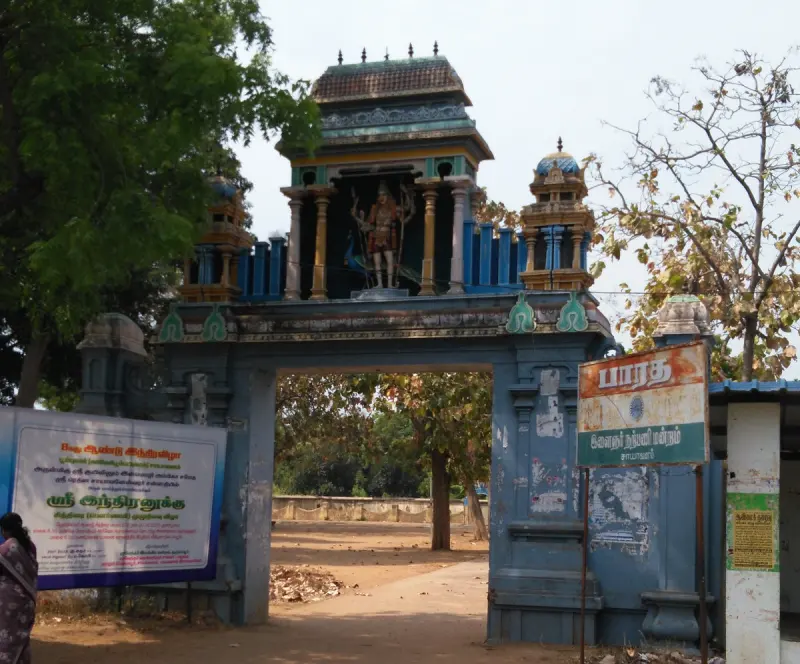 A blue and yellow gate tower with a standing figure above, and notice boards at its side