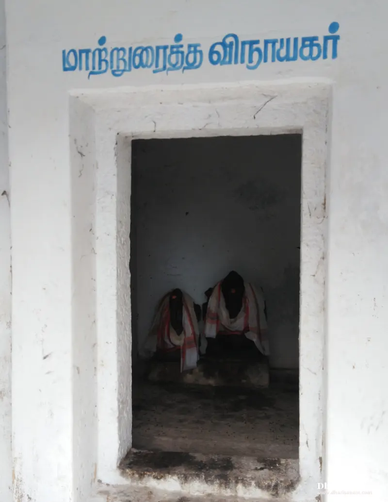 White doorway under the Tamil name of the shrine, with two small idols in cloth seen inside