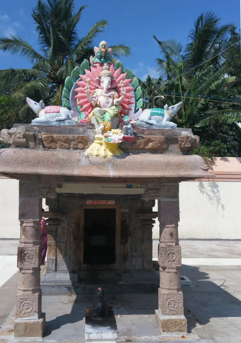 A small pillared shrine topped by a coloured stucco Vinayakar, with a Nandi in front