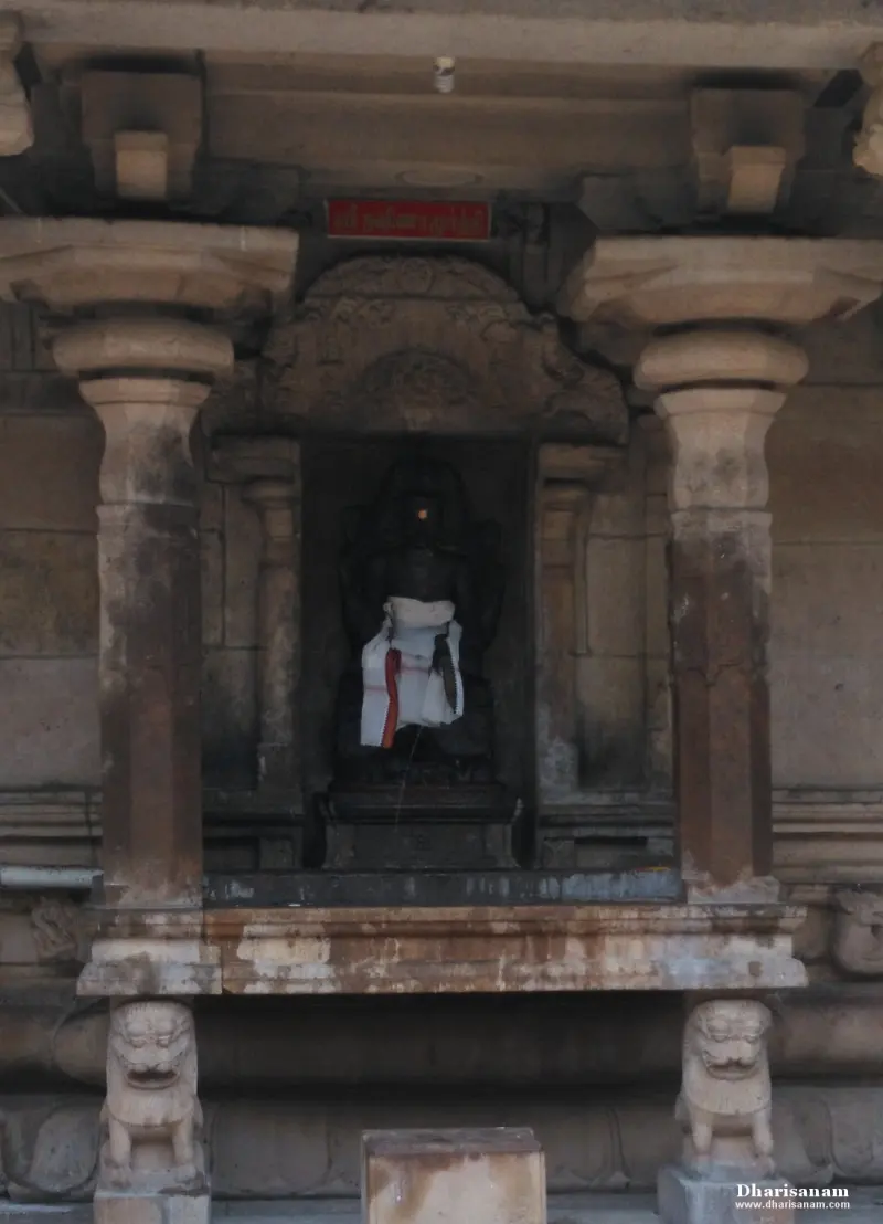 Dark seated idol with white cloth in a pillared stone niche