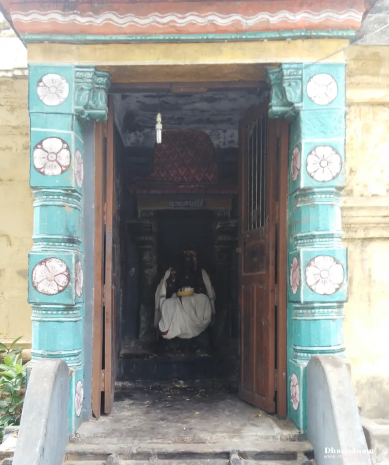 White-draped idol seen through a doorway framed by green floral pillars
