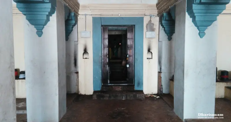 A blue-framed doorway with an open door at the end of a hall of white pillars with blue brackets