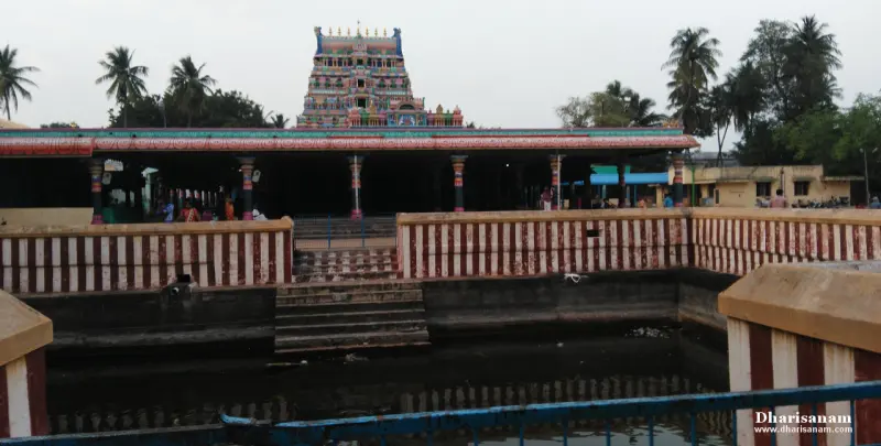 A tank with striped walls and steps, a pillared hall and a colourful tower behind it