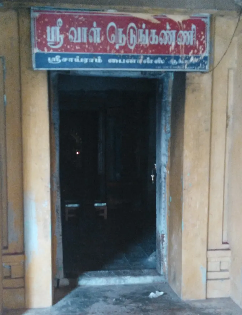 A dark doorway under a red Tamil name board of the goddess shrine