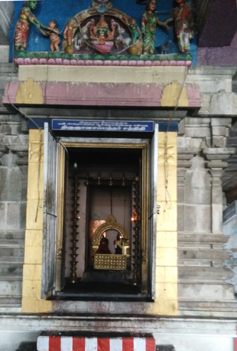 A shrine with a name board, lamp stands and a golden frame inside, and stucco figures above