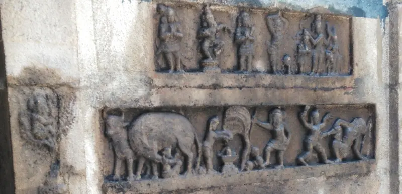 Two rows of stone relief panels showing many small figures, one row including an animal.