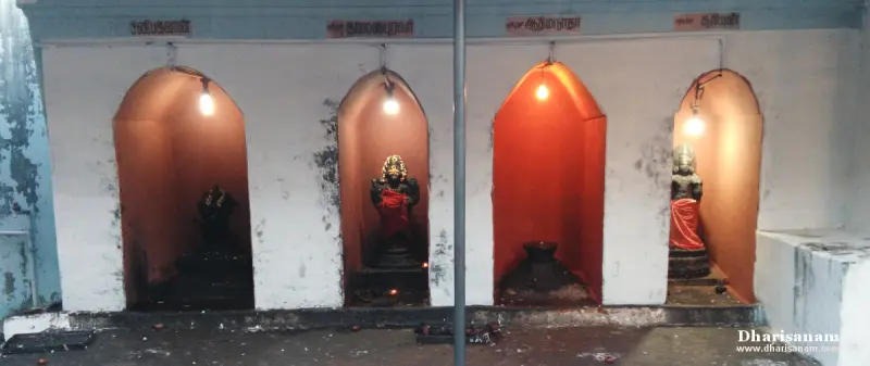 Four arched niches painted orange hold idols and a lamp-like stone, each with a lamp and a Tamil label above