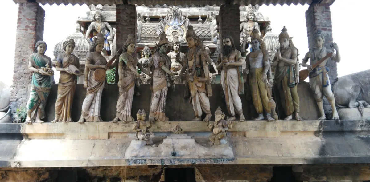 Standing and seated stone figures in a row against a shrine tower, several holding musical instruments.