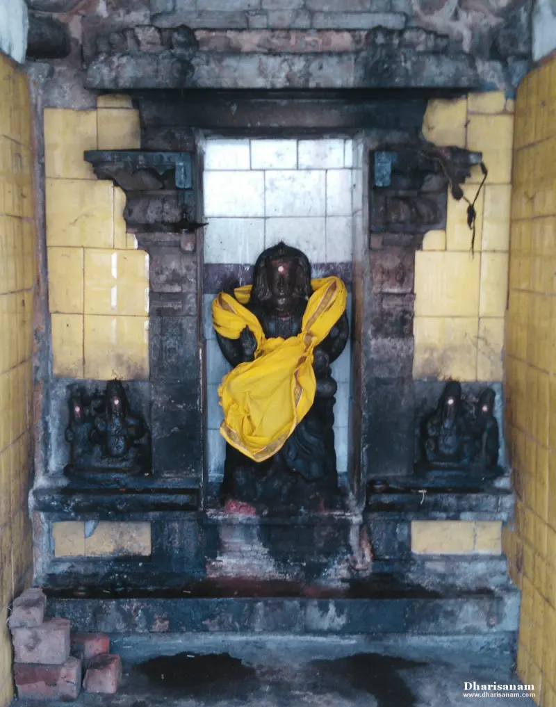 A dark stone idol wrapped in yellow cloth, with a smaller idol on each side.