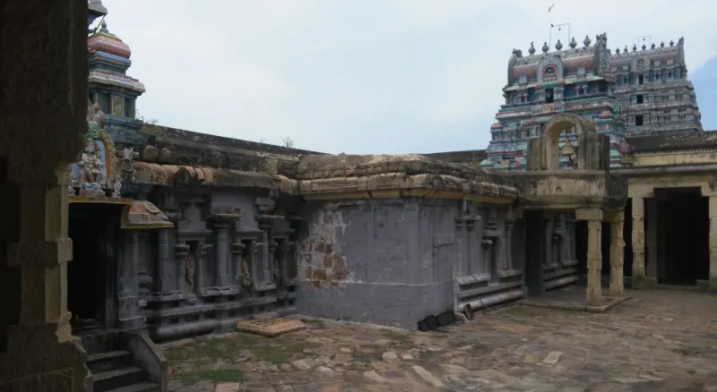 Stone shrine buildings in a courtyard with the gopuram to the right