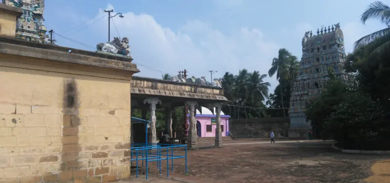 A wide paved courtyard with a pillared hall on the left and the tower on the right