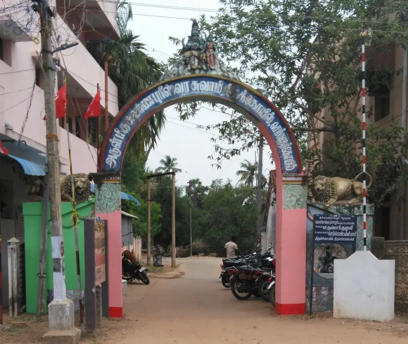 A painted arch with Tamil lettering and two figures on top, and lion statues at its sides.