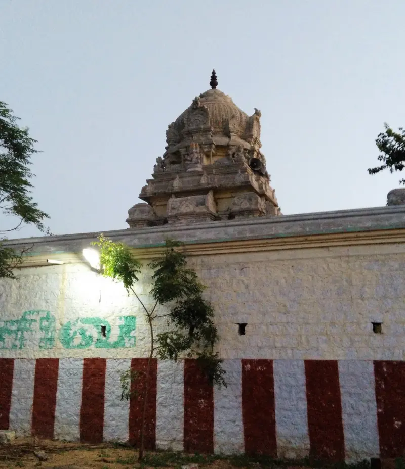 A stone tower with a domed top above a whitewashed wall painted with red and white stripes.