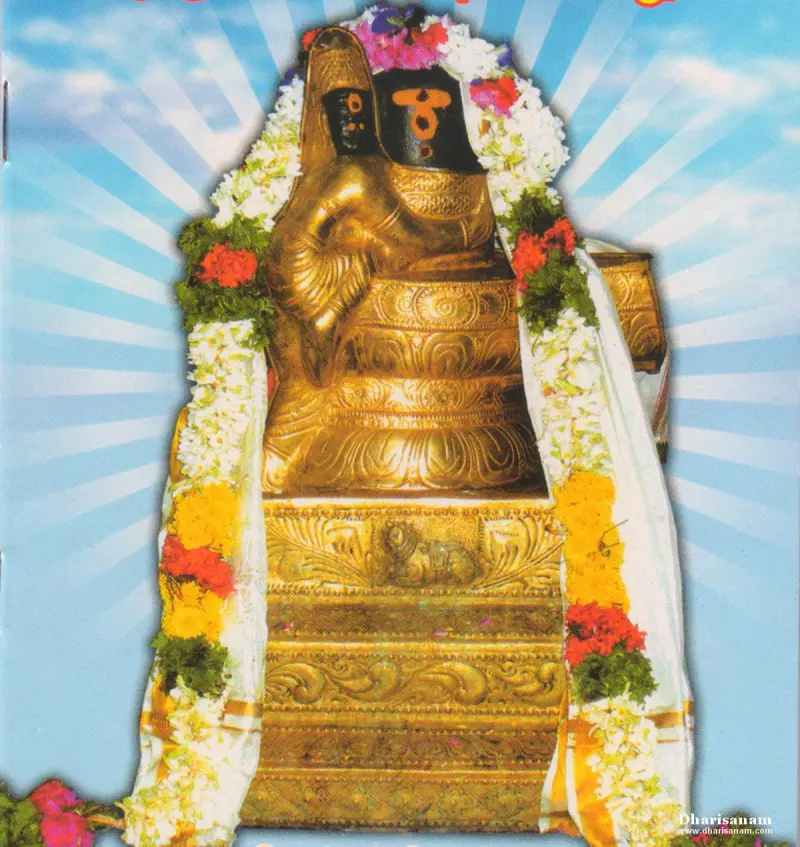 A gold-clad image on a stepped base, draped with flower garlands against a blue sky backdrop.