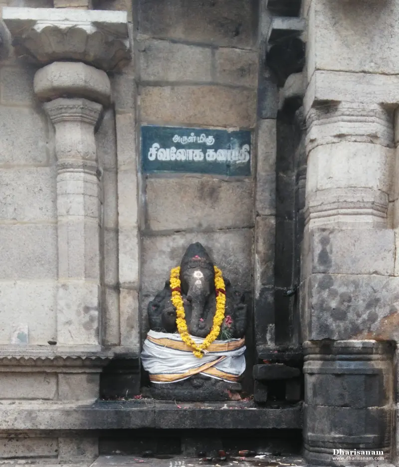 A dark stone Vinayakar with a yellow garland in a niche, under a green board naming Sivaloka Ganapathy