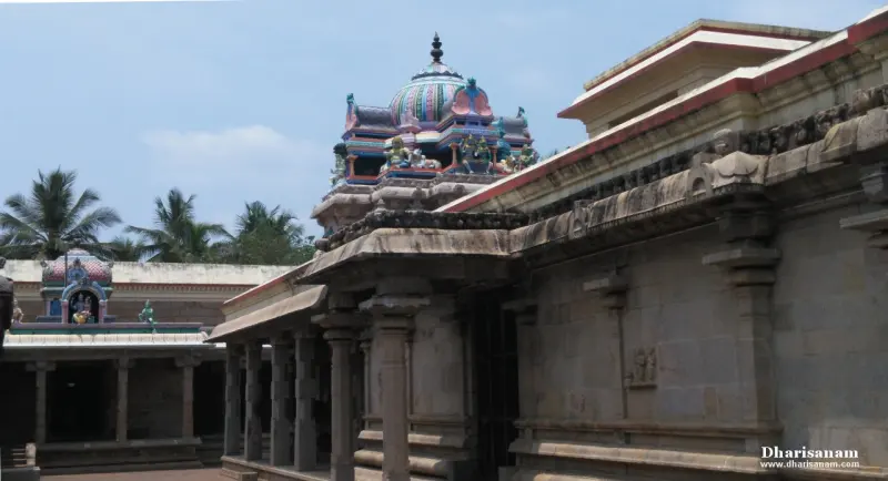 Painted dome tower with sculptures rising above stone corridor roofs