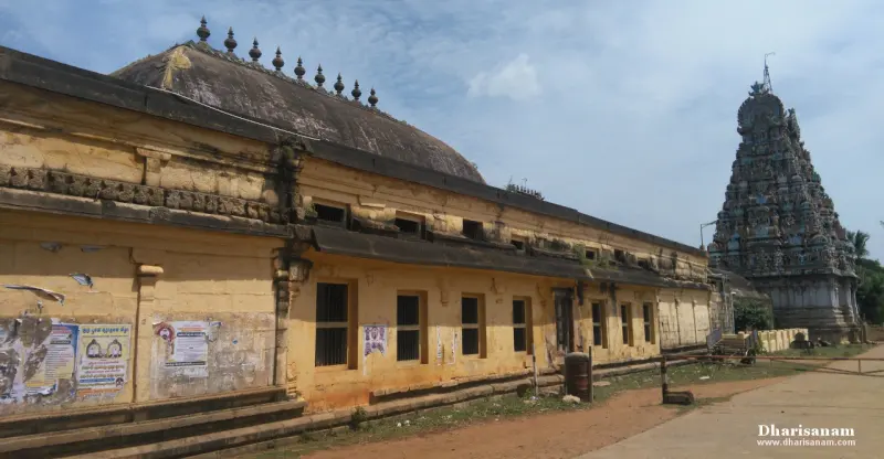 A long yellow-walled hall with a curved roof, and a dark tower on the right