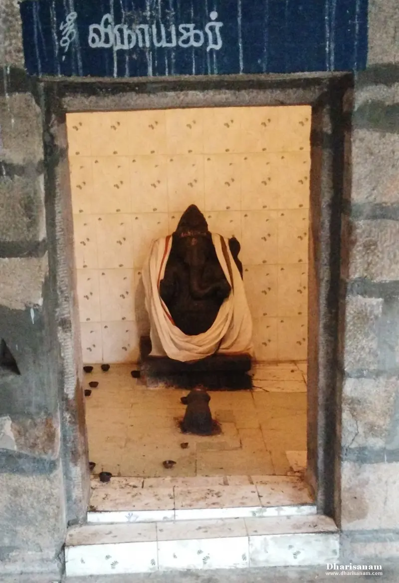 Black Vinayakar idol draped in white cloth under a Tamil name board
