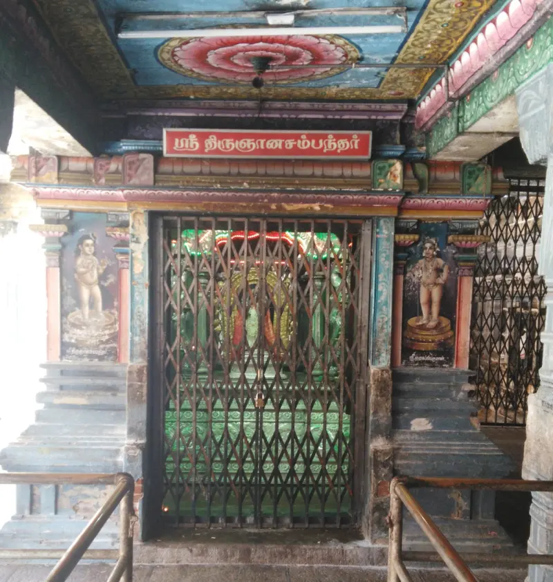 A shrine with a name board and a child figure painted on each side of an iron gate