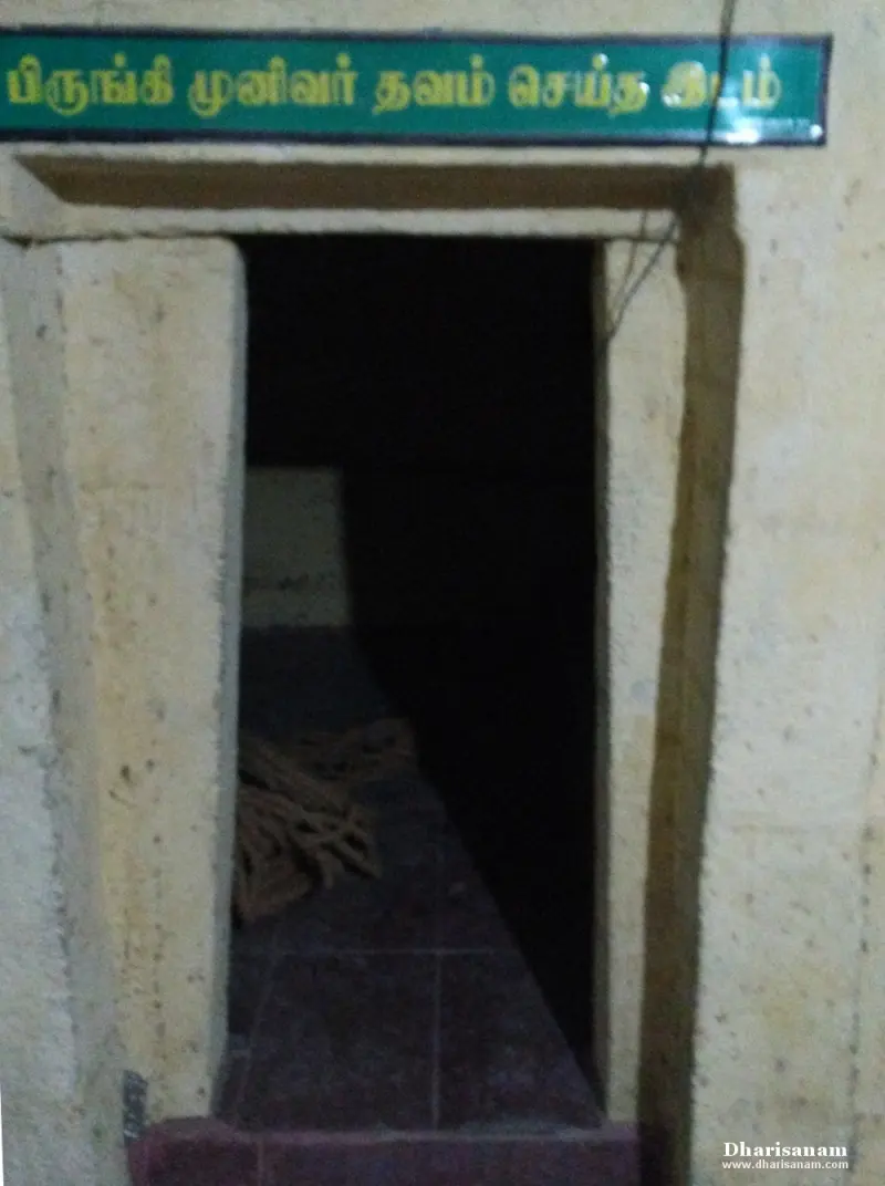 A low doorway into a dark room, with a green sign above it naming the place