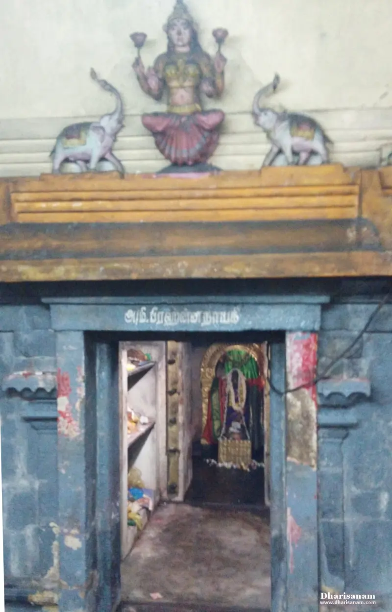 A doorway under a Tamil name board, with a lotus-holding goddess figure between two elephants above