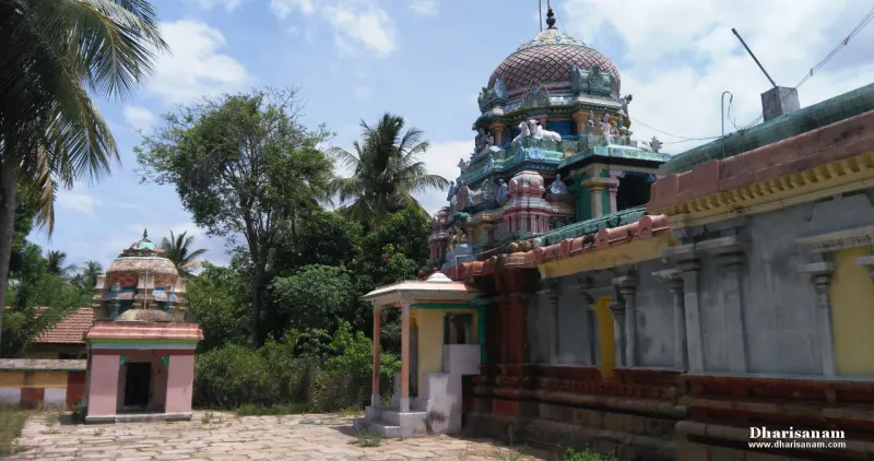 The domed tower rising over the corridor wall, with a small shrine on the left and palm trees behind