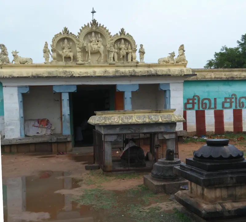 A porch crowned with painted figures of Shiva, Parvathi and others, with a Nandi pavilion and a black stand in front.