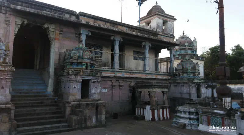 Stone steps climb to a pillared hall beside small domed shrines, with the dark flagstaff at the right edge
