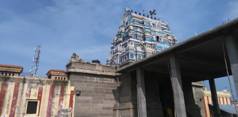 Colourful three-tier tower rising behind a granite wall and hall roof