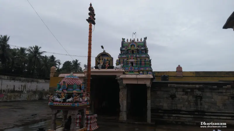 Tall flagstaff beside a small shrine and the entrance, with a painted tower behind