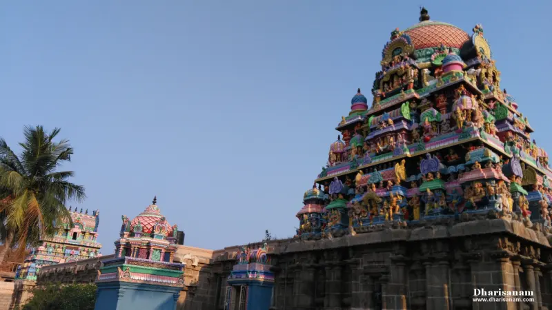 Tall painted tower on the right with smaller towers at the left, and a coconut palm, against a blue sky
