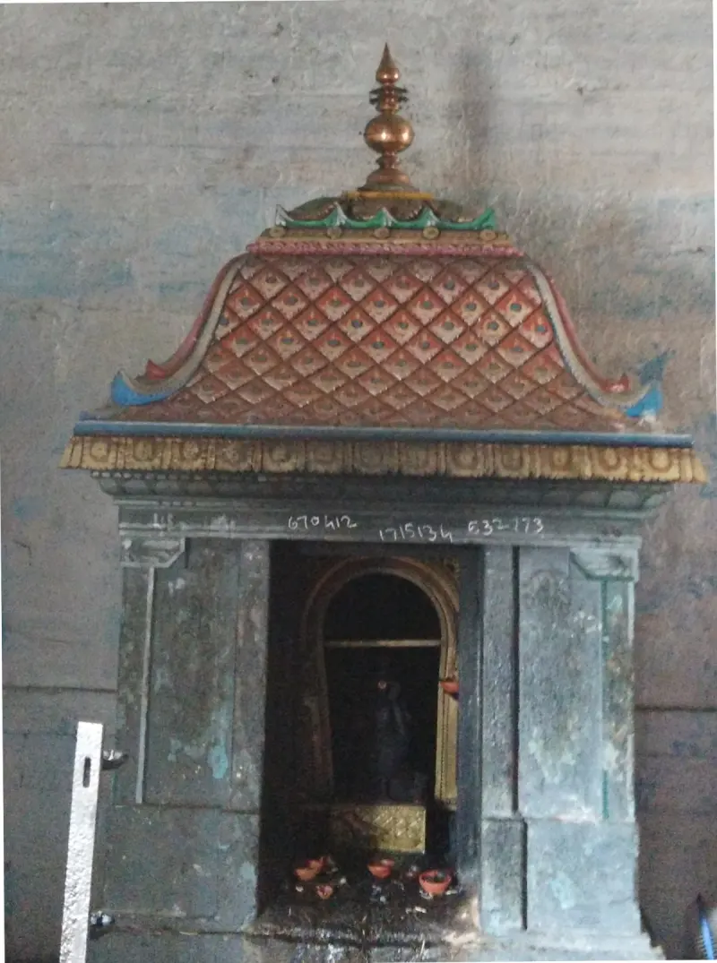 A small shrine with a diamond-patterned roof and oil lamps at its base