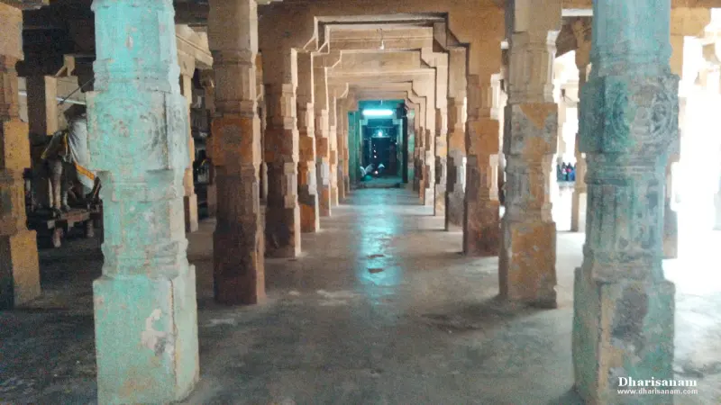 A long hall of stone pillars with a lit doorway at the far end