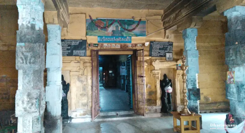 A shrine doorway with guardian statues and a lamp stand