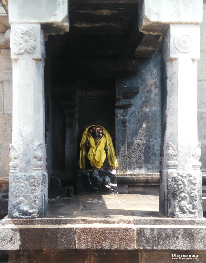 Stone pillars frame a dark niche holding a small idol covered in a yellow cloth