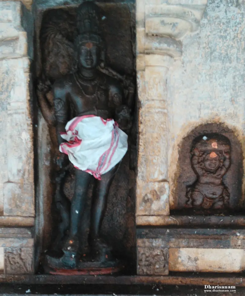 Standing stone figure in a niche, with a white cloth at the waist and a small carving beside it
